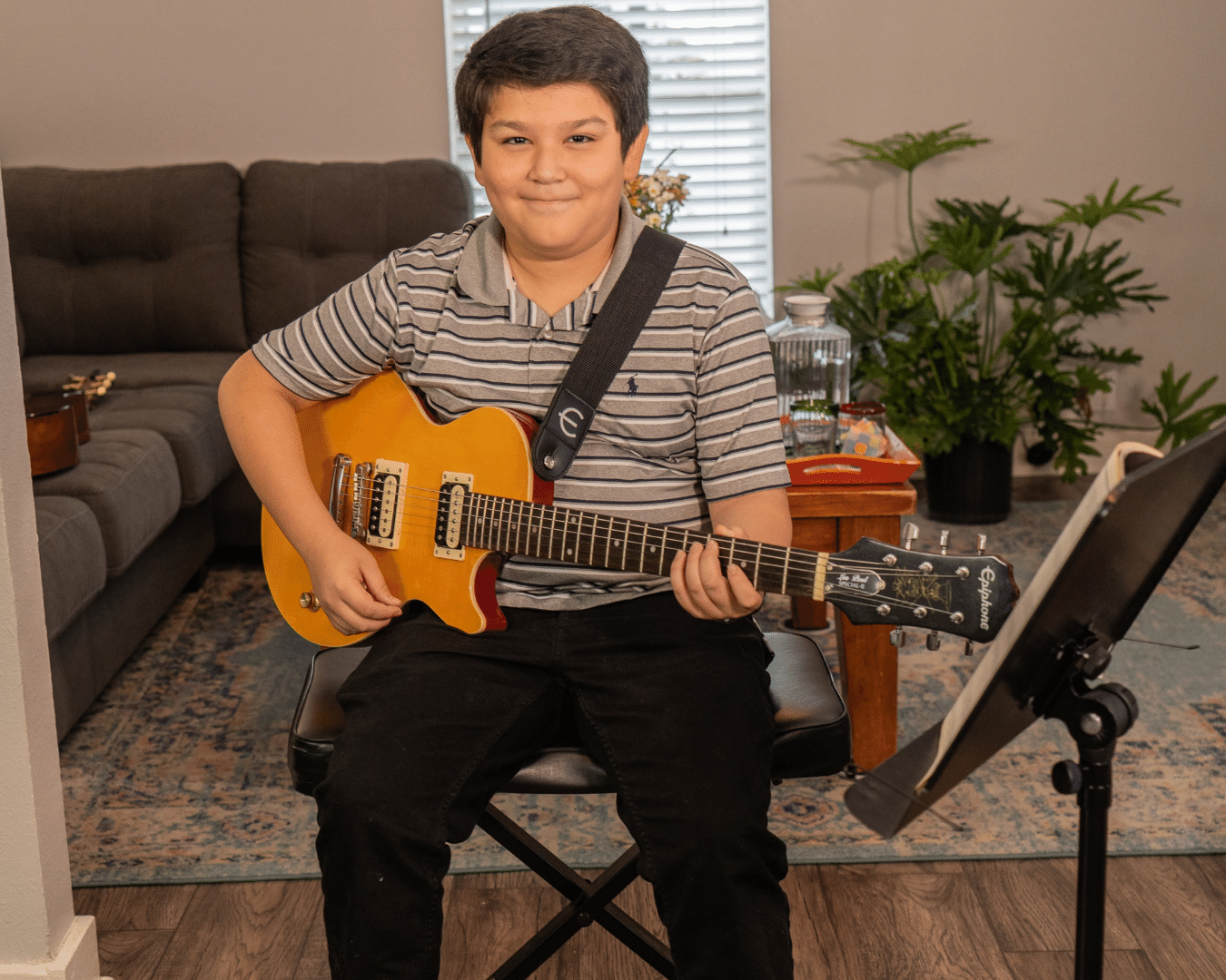 Smiling boy hold an electric guitar. Happy guitar student.