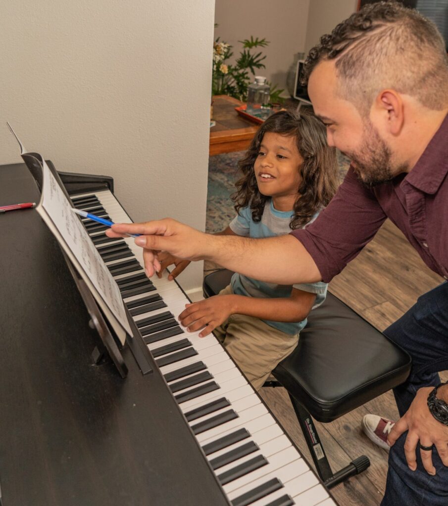 Mr. Jose showing a boy student sheet music instruction on the piano