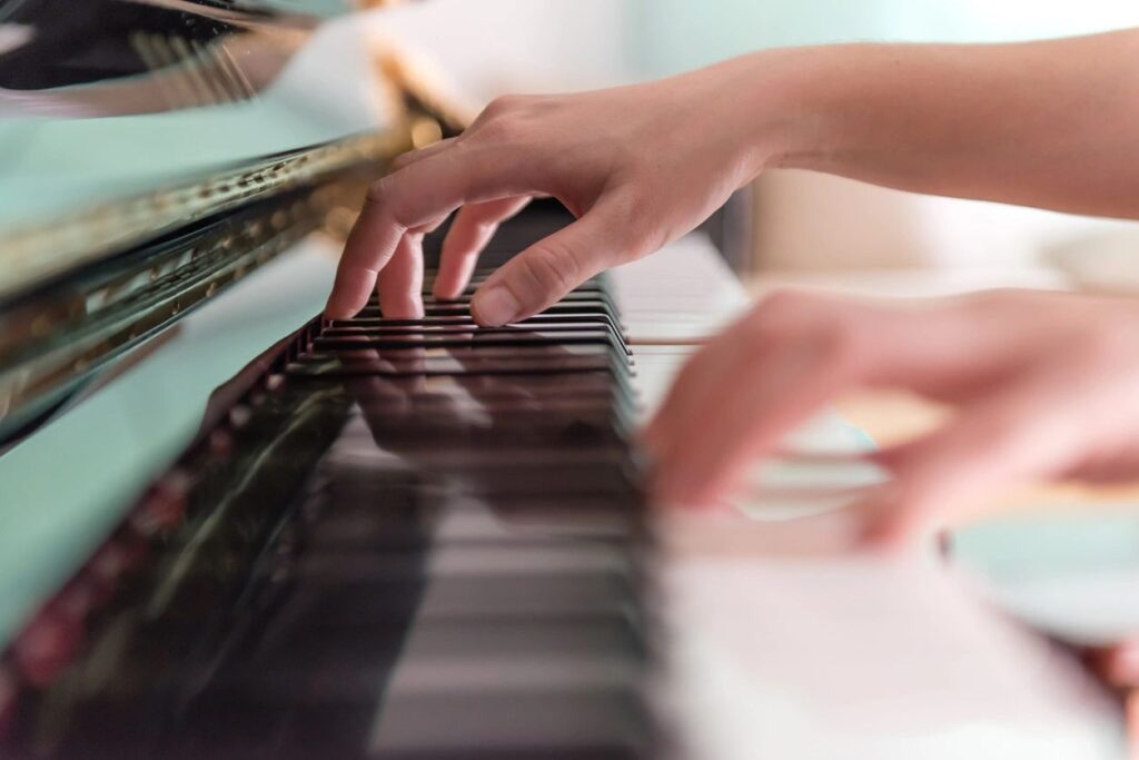 Close up shot of a piano keyboard and hand playing the keys.